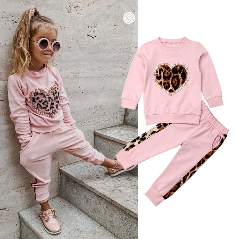 Pink children's outfit with leopard print heart design on a concrete staircase.