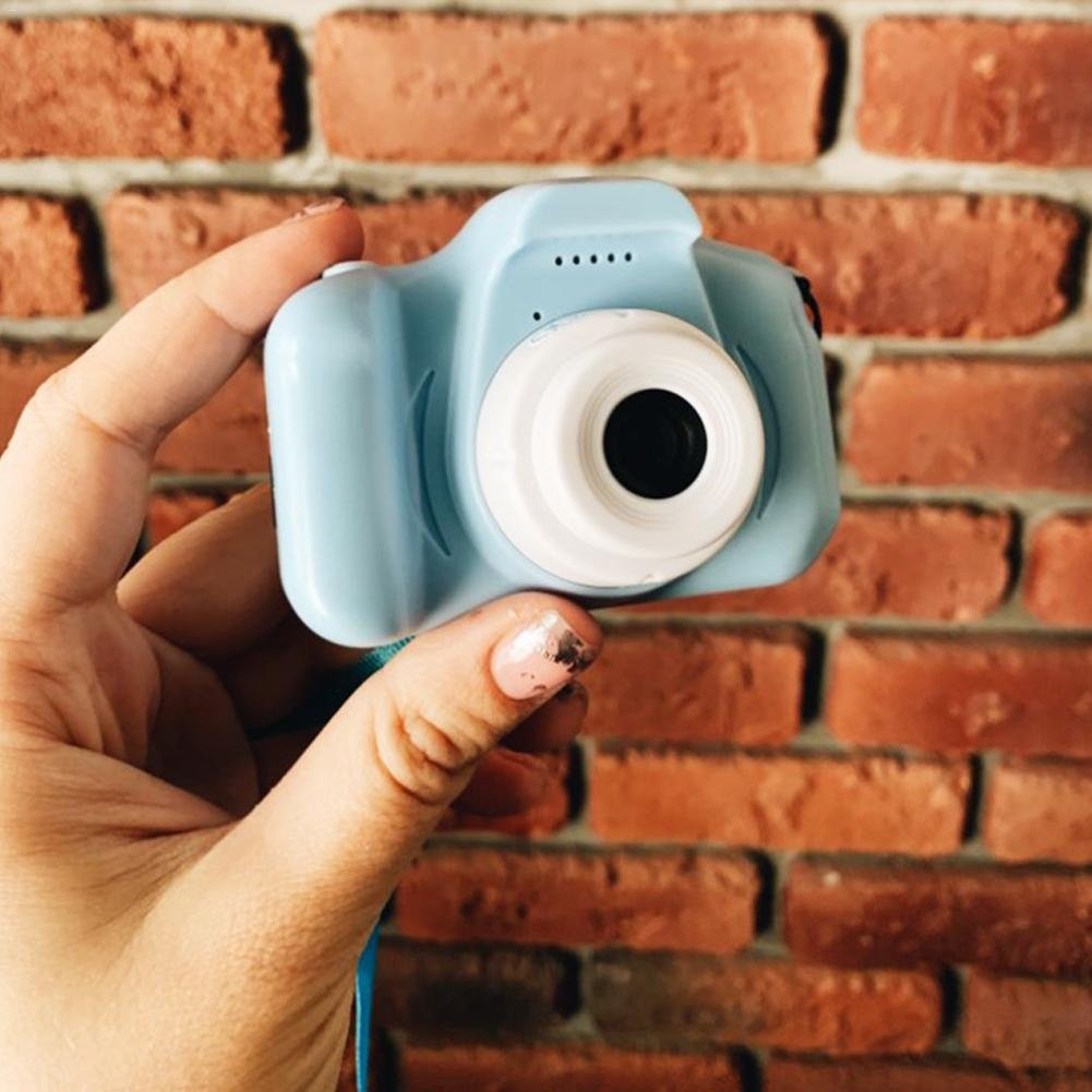 Hand holding a small blue camera against a brick wall