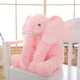 Large pink elephant plush toy on a white surface with a light wooden grid background