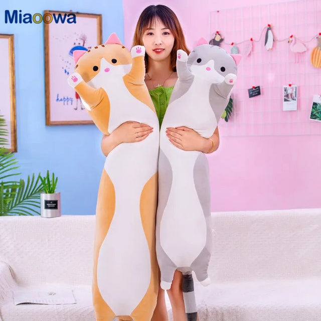 Person holding two large plush toys resembling a fox and a raccoon in a room with a pink wall and plants.