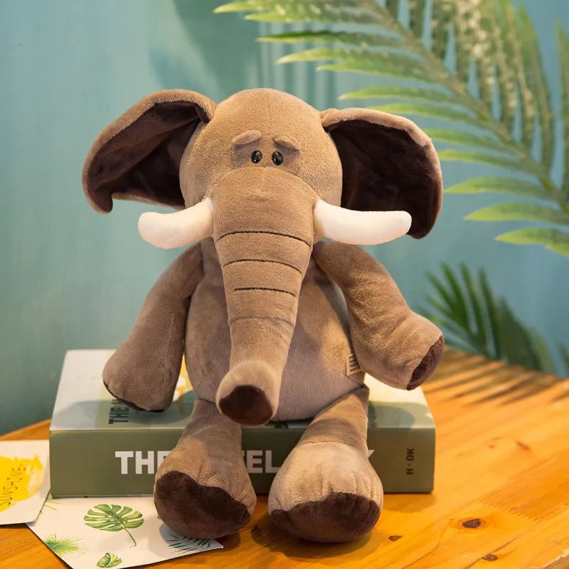 Plush elephant toy on a book with a green plant in the background
