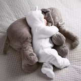 Plush elephant toy and baby in white outfit on a textured surface