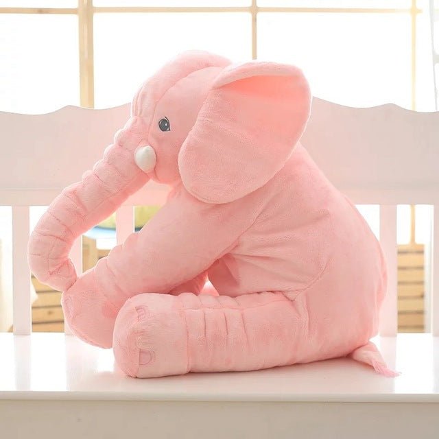 Pink elephant plush toy on a white surface with a light-colored wall.