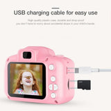 Pink children's camera with USB charging cable on a white background