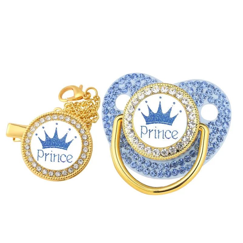 Decorative pacifier with 'Prince' text and crown design, gold and blue color scheme.