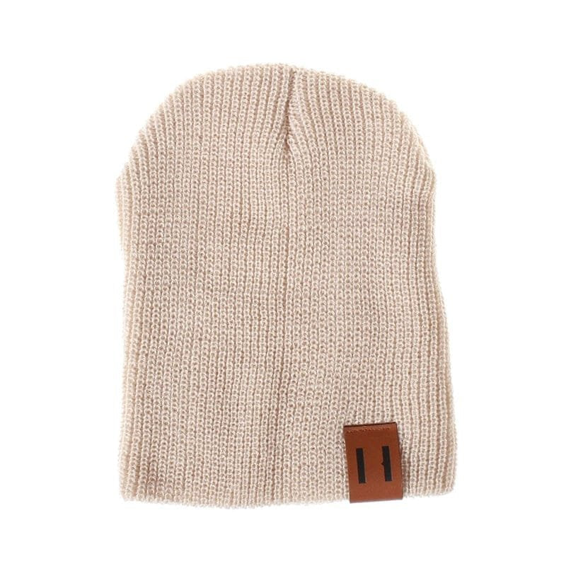 Beige knit beanie with a brown leather patch on a white background