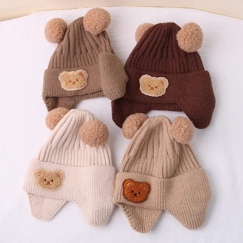 Four knitted hats with bear face designs and pom-pom ears on a white background.
