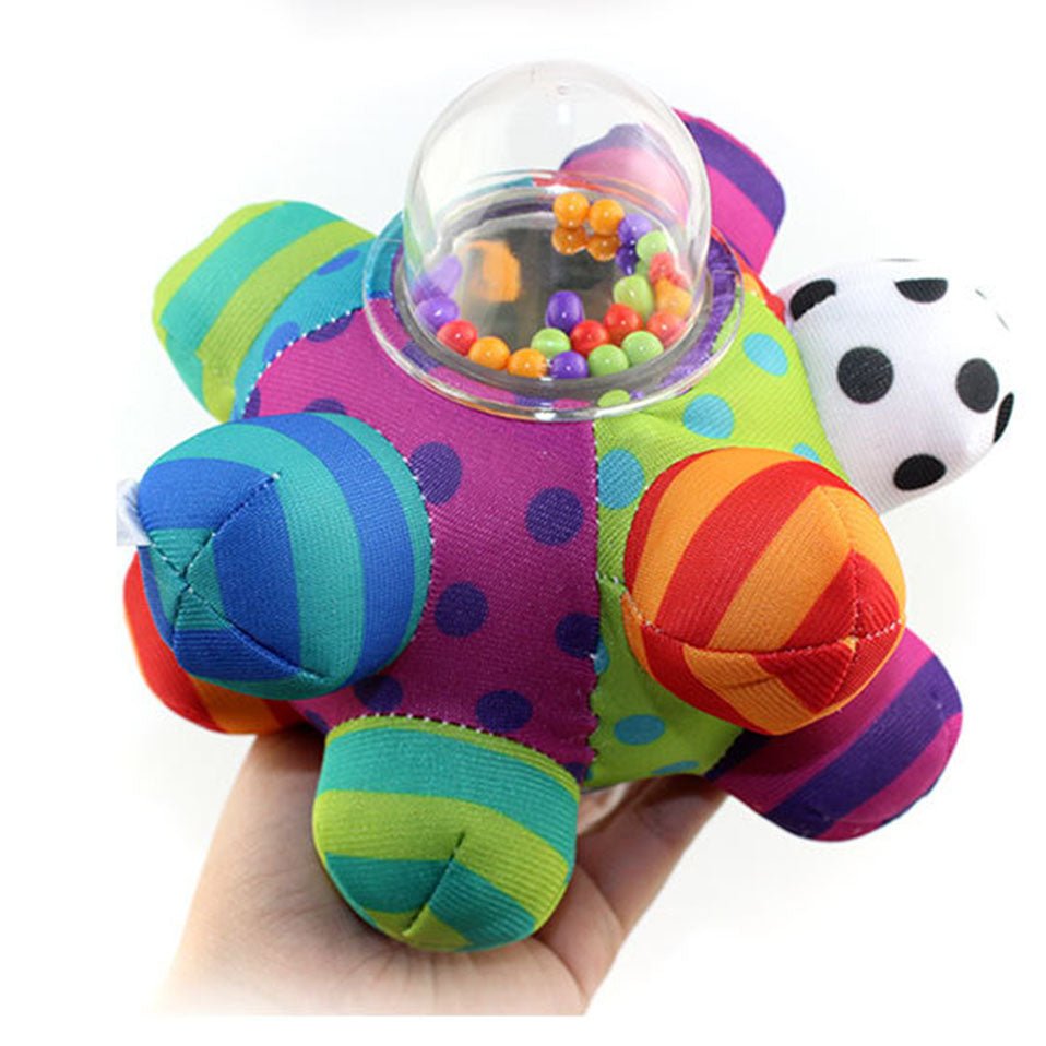 Colorful baby toy with a transparent ball filled with beads, held in a hand against a white background.