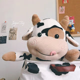Plush cow toy with black spots on a white wall background