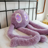 Purple plush toy with heart eyes on a bed
