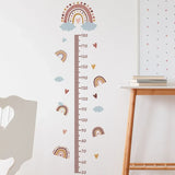 Height chart with rainbow and cloud design on a wall next to a wooden table.