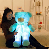 Person holding a glowing blue teddy bear in a room setting