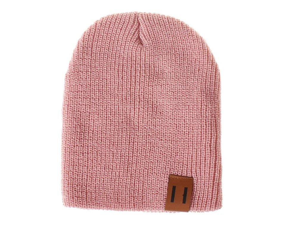Pink knit beanie with a brown label on a white background