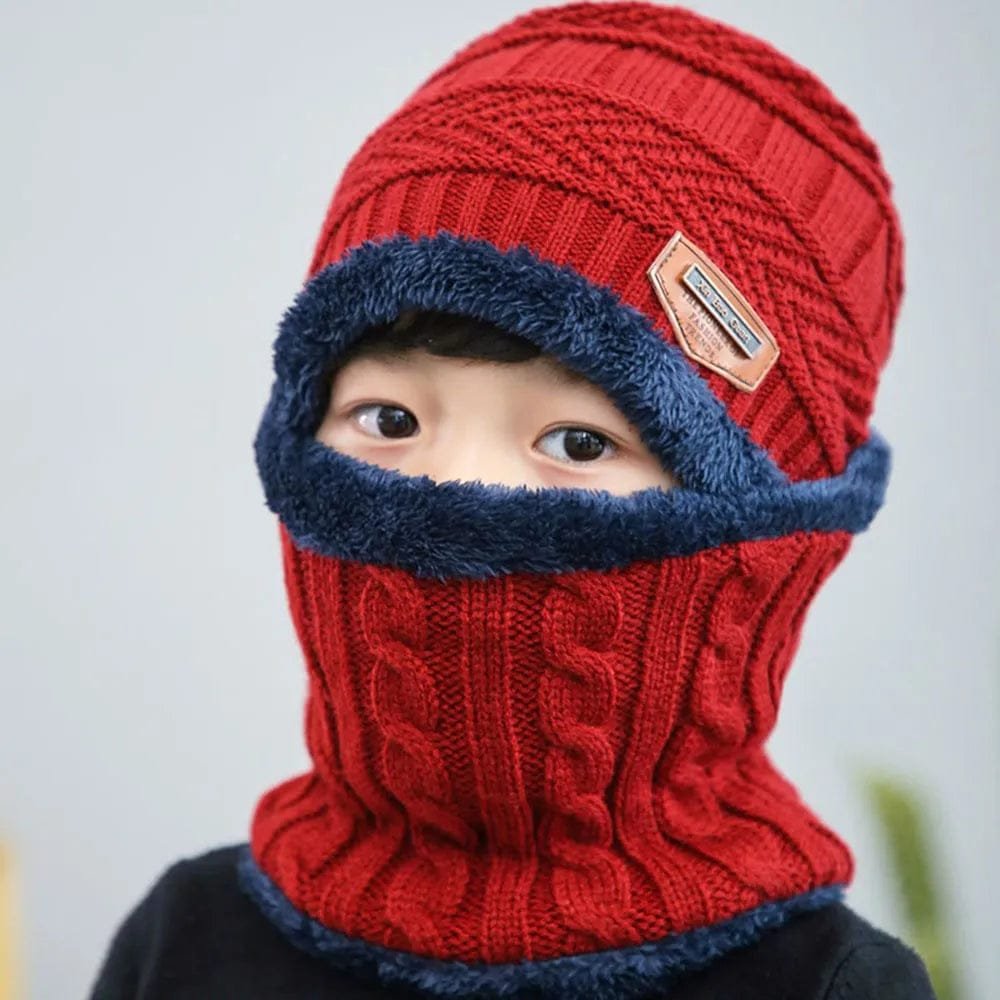 Child wearing a red knitted hat and scarf with a blue trim against a light background