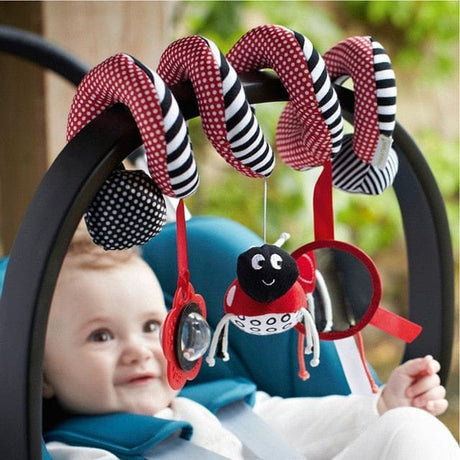 Baby in a stroller with colorful carabiner toy featuring a ladybug design.