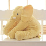 Yellow elephant plush toy on a white surface with a light background