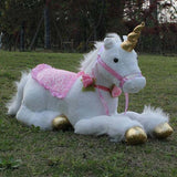 Plush unicorn toy with pink saddle blanket and gold hooves on grass