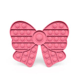 Pink bow-shaped pop-it fidget toy on a white background
