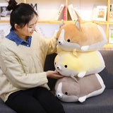 Person holding a plush toy shaped like a dog with a yellow body and brown legs on a couch.