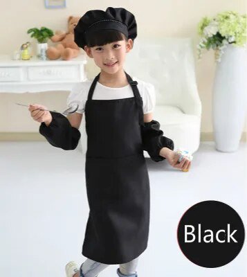 Child wearing a black apron and chef hat in a kitchen setting