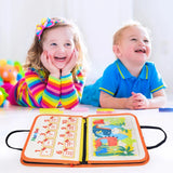 Two children sitting at a table with a colorful educational book open in front of them.