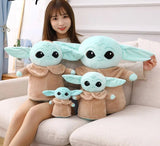 Person holding three Baby Yoda plush toys on a couch