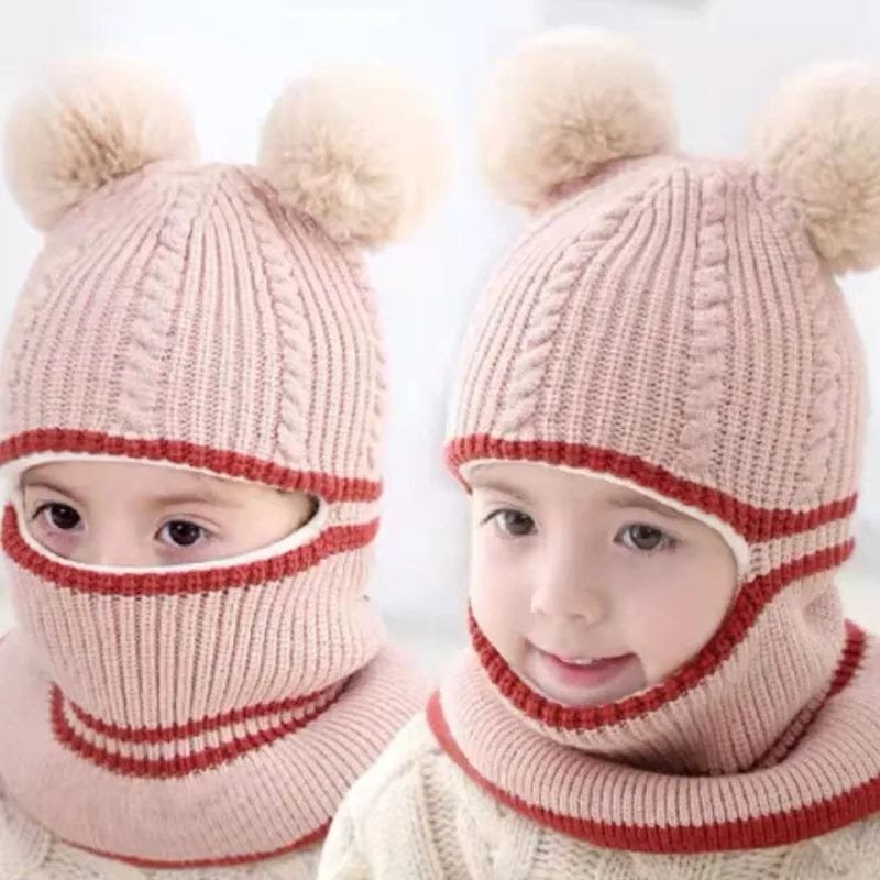 Two children wearing pink knitted hats with pom-poms and red accents.
