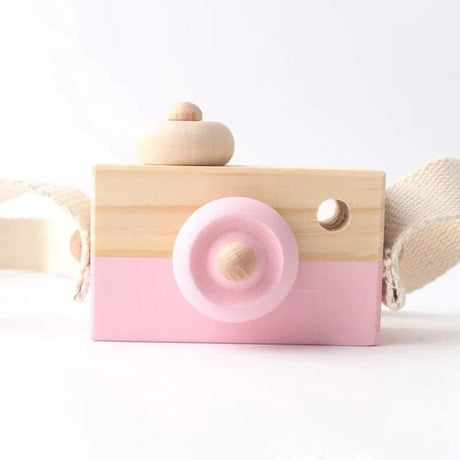 Wooden toy camera with pink lens on a white background