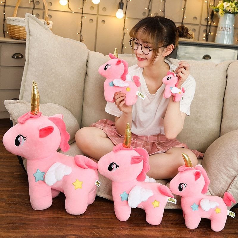 Person sitting on a couch holding pink unicorn plush toys in a cozy living room.