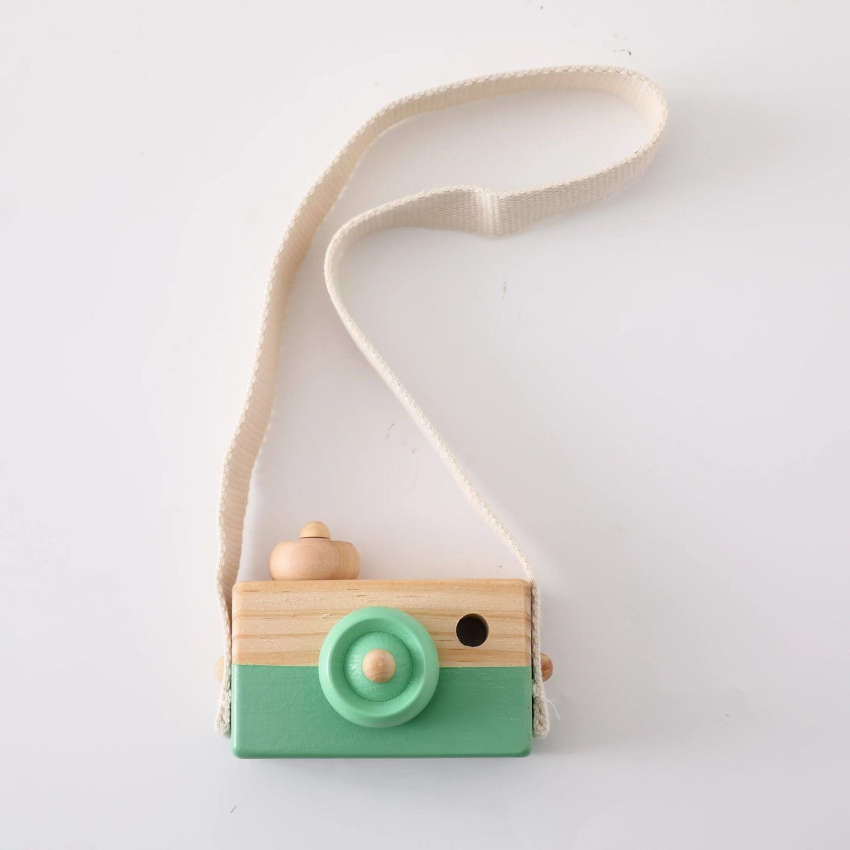 Wooden toy camera with a green base and beige top on a white background