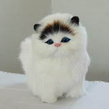 Stuffed toy cat with white fur, black and brown ears, and blue eyes on a light background