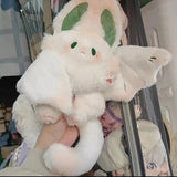 Plush toy resembling a dragon held by a person, with a blurred background