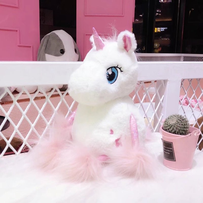 Plush unicorn toy with pink hair on a white surface with a pink background