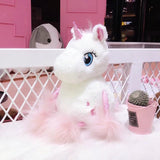 Plush unicorn toy with pink hair on a white surface with a pink background