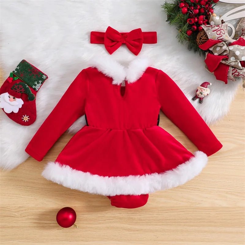Red Santa Claus outfit with white fur trim on a wooden surface with Christmas decorations.