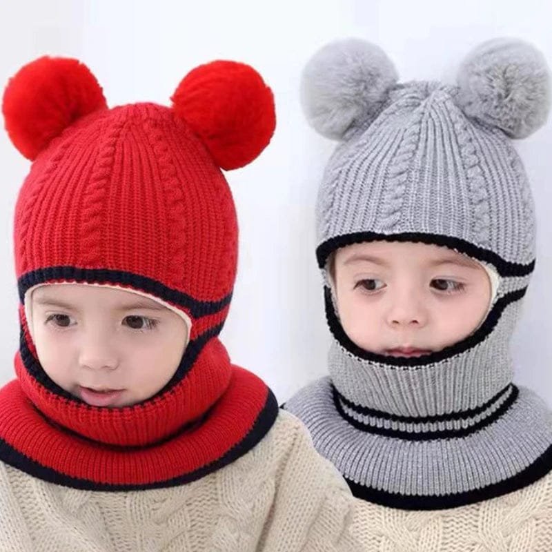 Two children wearing red and gray knitted hats with pom-poms on a white background.