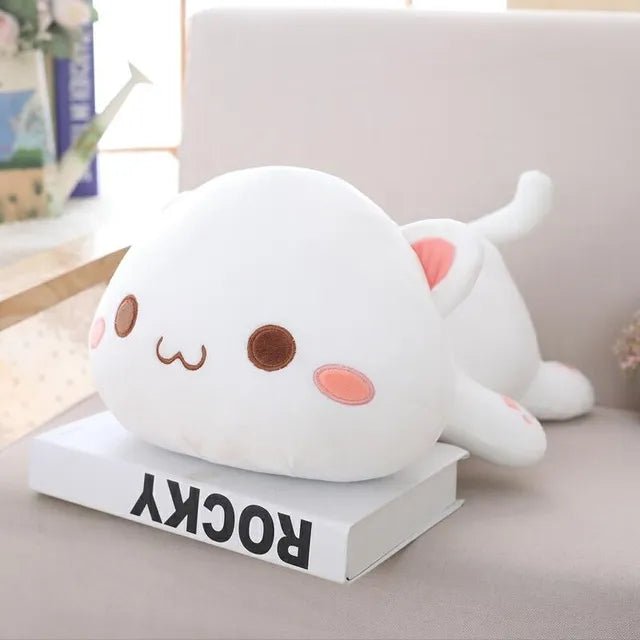 Cute white plush toy resembling a cat on a book with a blurred background