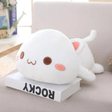 Cute white plush toy resembling a cat on a book with a blurred background