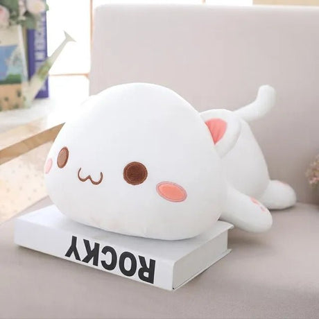 Cute white plush toy resembling a cat on a book with a blurred background