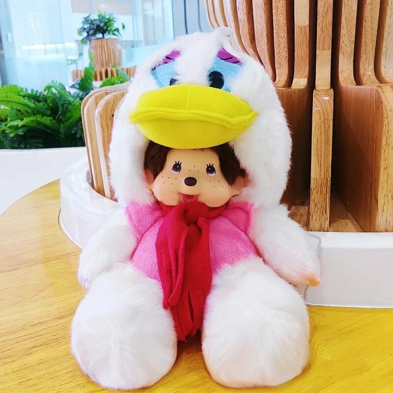 Plush toy with a white hood, yellow beak, pink scarf, and black eyes on a wooden surface.