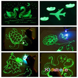 Glowing drawings on a dark surface with 'Kidsbelie' branding.