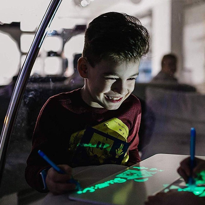 Child using a glowing tablet with a blue stylus in a car.