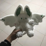 White plush toy with bat wings held by a hand on a tiled floor
