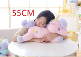 Person holding a large pink and purple plush toy with '55CM' text above, sitting on a white table.