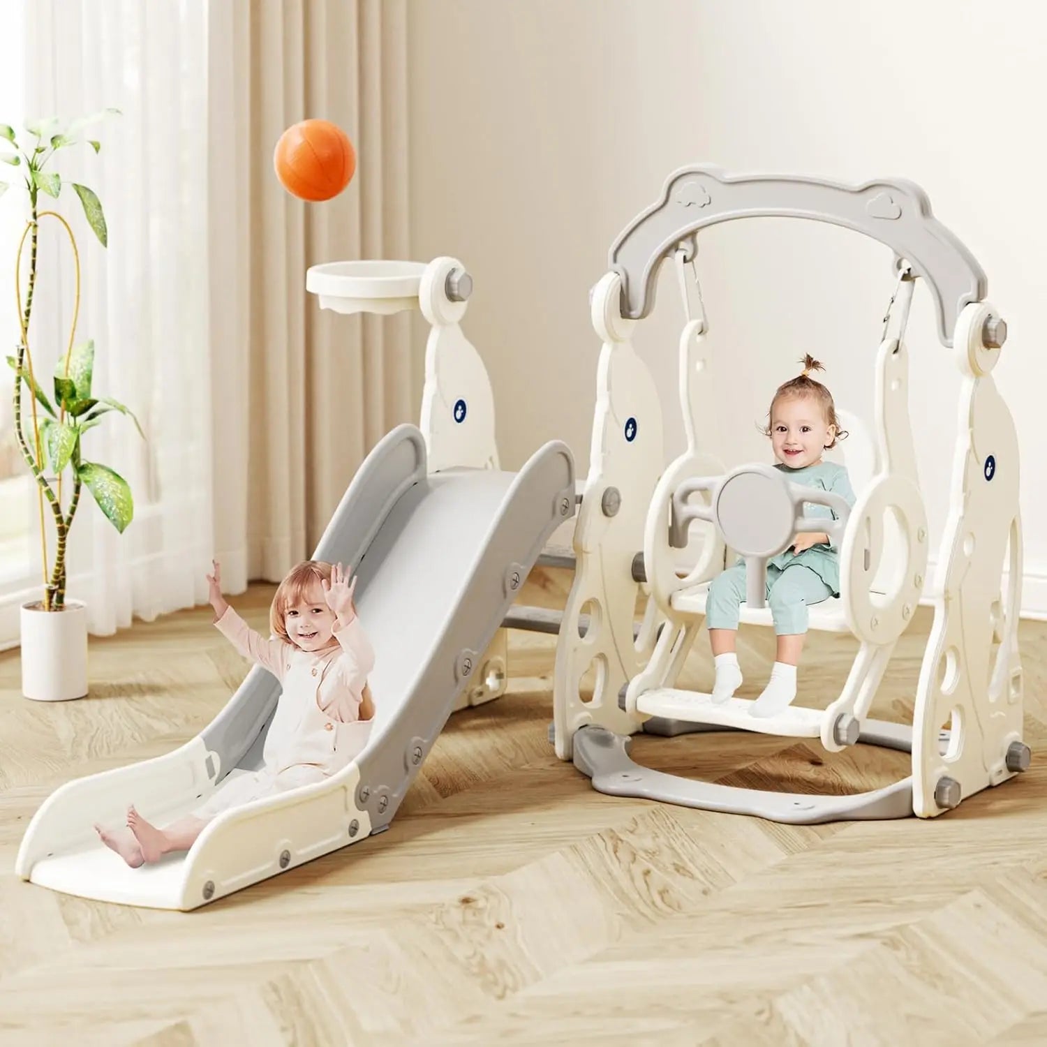 Children's play structure with slide and swing in a room with curtains and plant.
