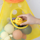 Yellow mesh storage bag with bath toys, including a yellow rubber duck, on a tiled bathroom floor.