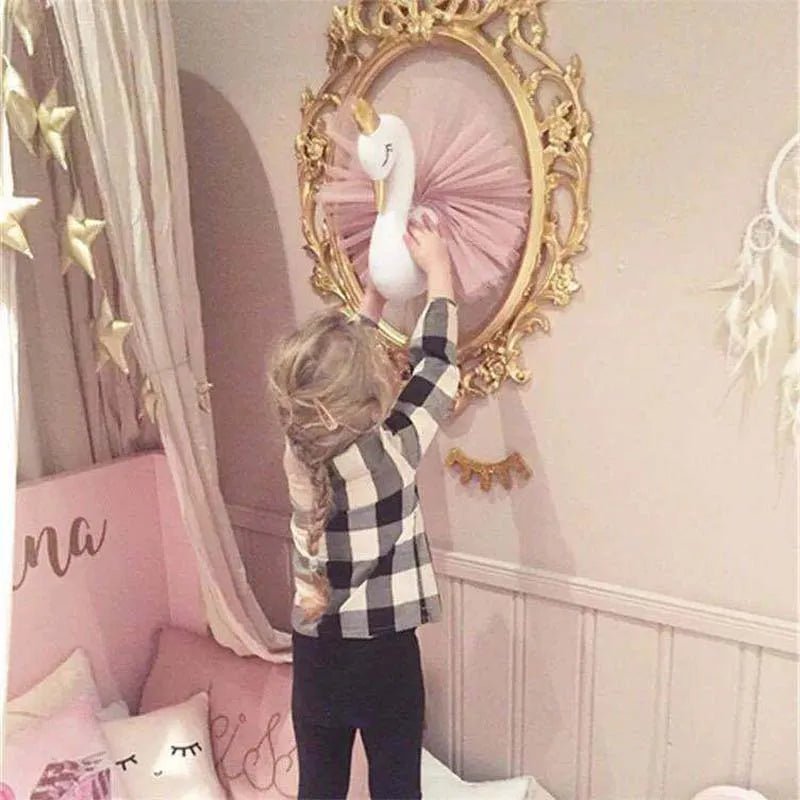 Child playing with a toy swan in front of a decorative mirror in a pink-themed room.