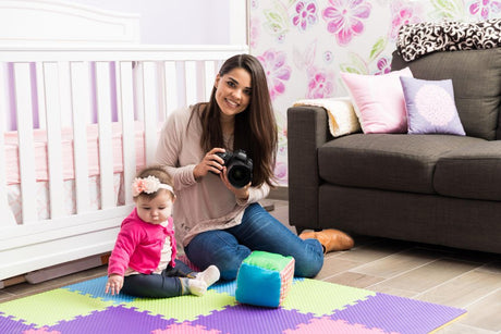 Woman with a camera and a child on a colorful mat in a nursery