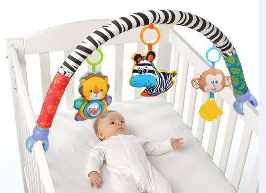 Baby lying in a crib with colorful baby gym toys hanging above
