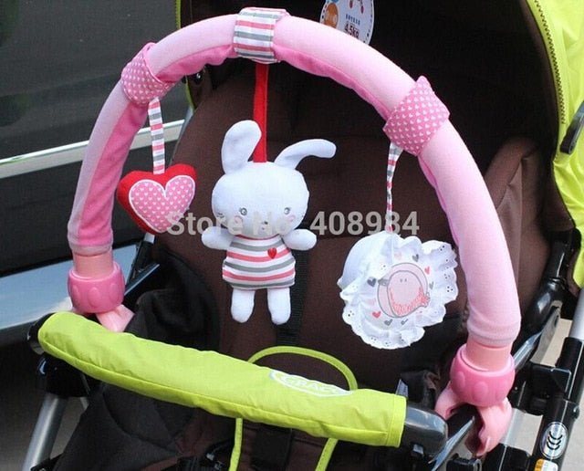 Pink baby car seat arch with toys hanging from it, attached to a stroller.